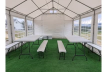 Un conjunto de mesa de catering plegable de 180 cm + 2 bancos en una carpa de fiesta